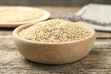 Photo of Brown rice in bowl on wooden table, closeup