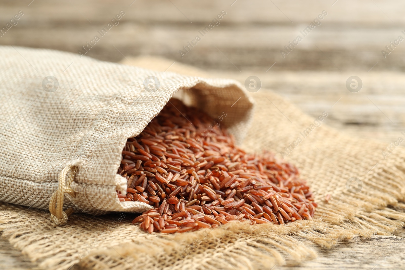 Photo of Brown rice in sack on table, closeup