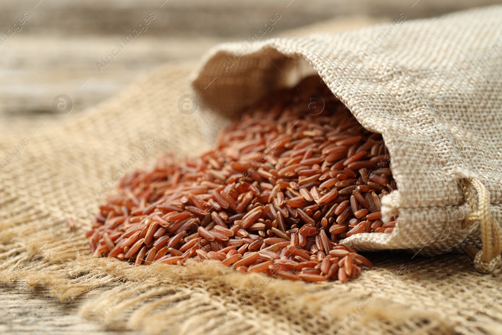 Photo of Brown rice in sack on table, closeup