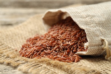 Photo of Brown rice in sack on table, closeup