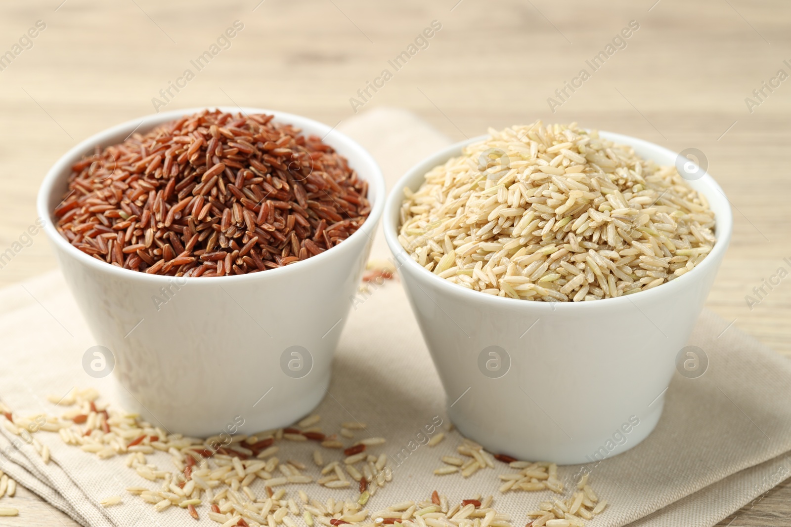 Photo of Different types of brown rice in bowls on table, closeup