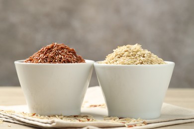 Photo of Different types of brown rice in bowls on table, closeup