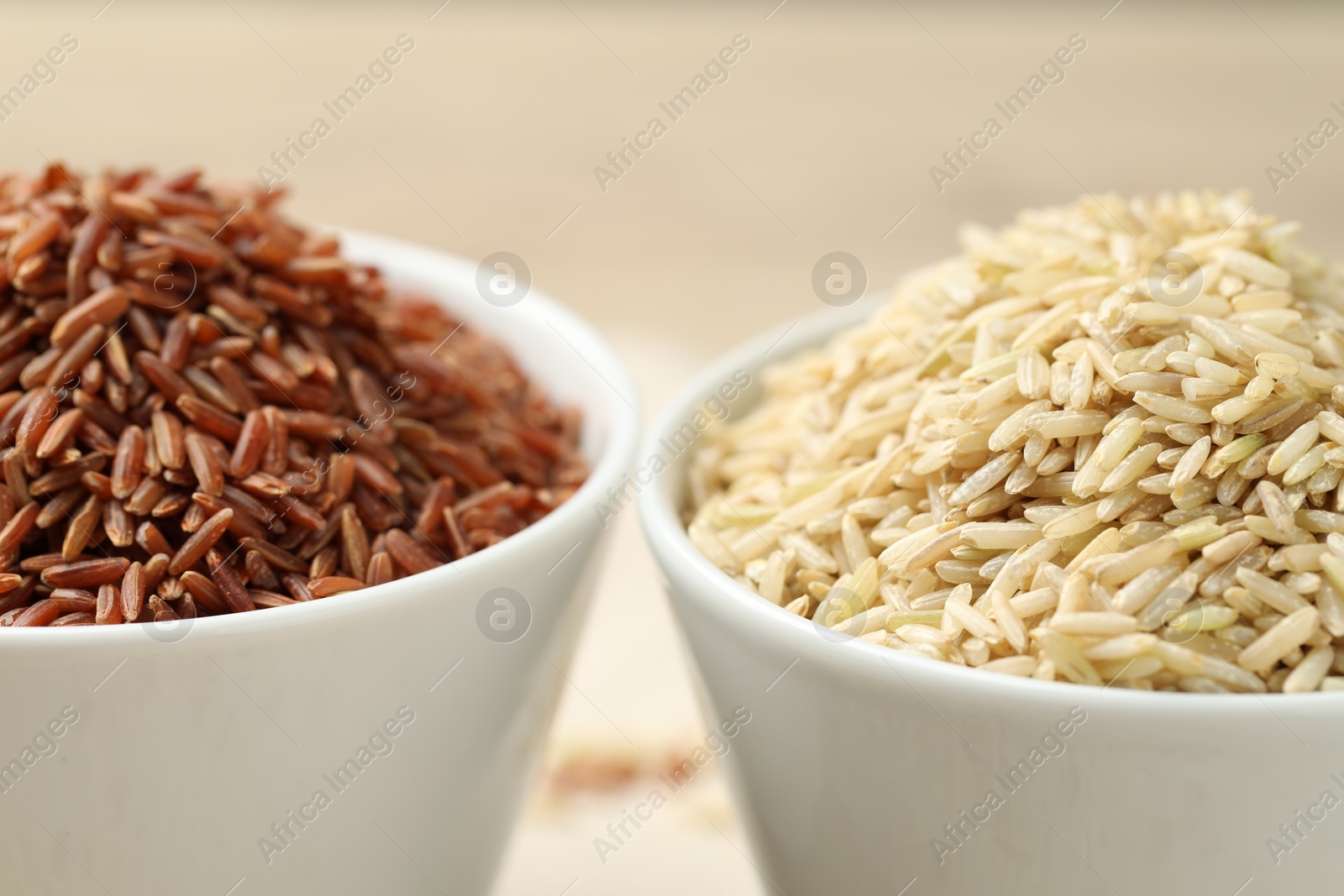 Photo of Different types of brown rice in bowls on blurred background, closeup