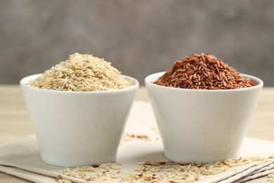 Photo of Different types of brown rice in bowls on table, closeup