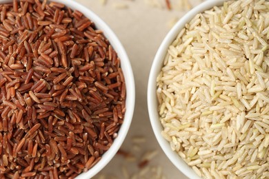 Photo of Different types of brown rice in bowls on table, flat lay