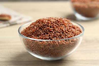 Photo of Brown rice in glass bowl on wooden table, closeup