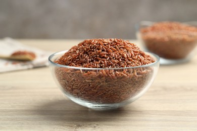 Photo of Brown rice in glass bowl on wooden table, closeup