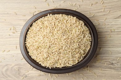 Photo of Brown rice in bowl on wooden table, top view