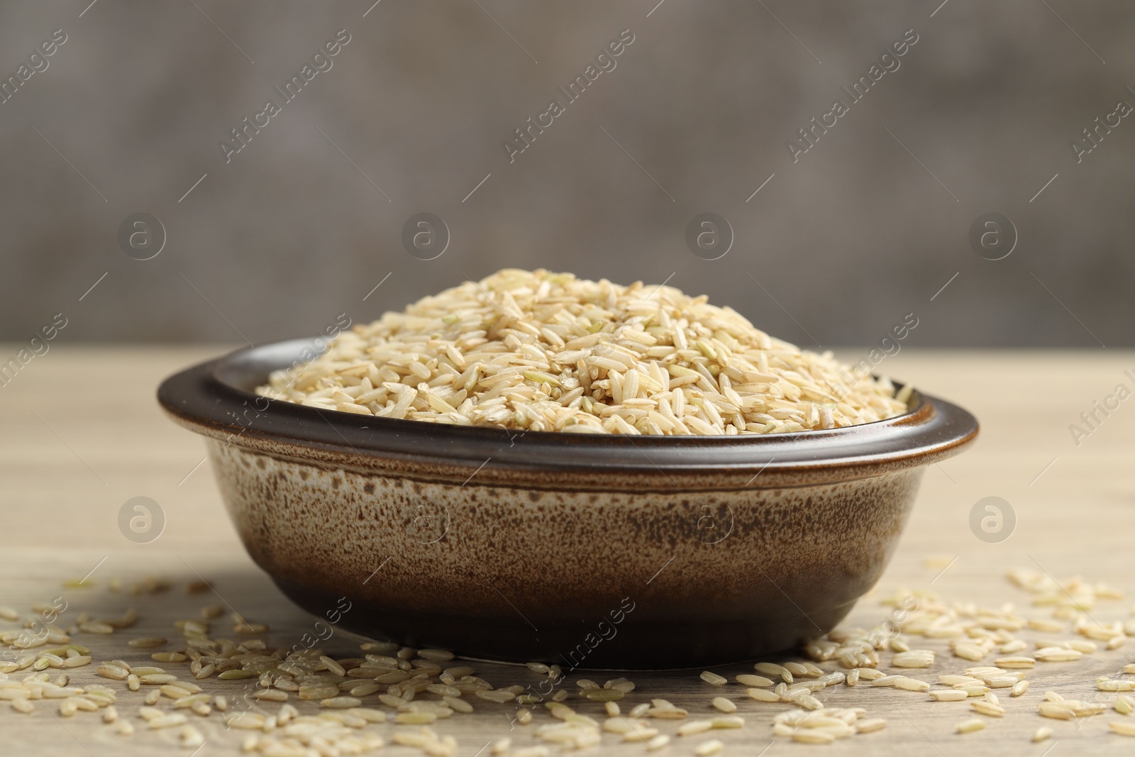 Photo of Brown rice in bowl on wooden table, closeup