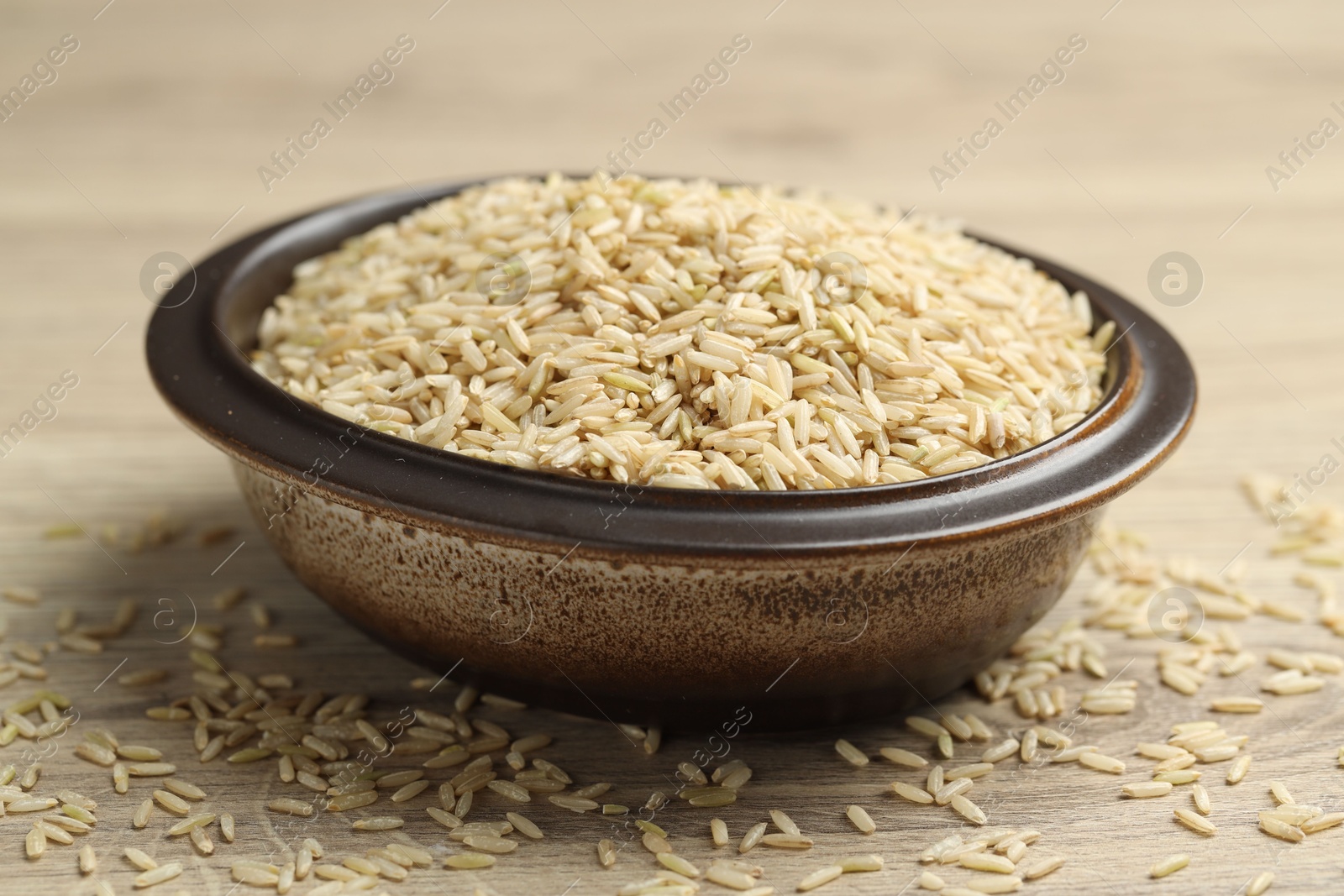 Photo of Brown rice in bowl on wooden table, closeup