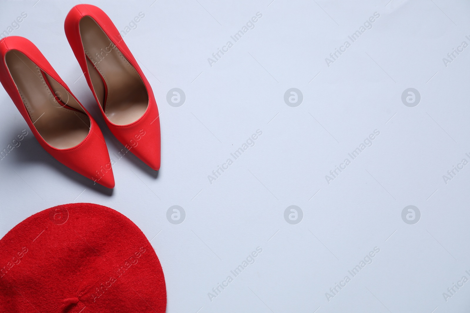 Photo of Pair of red high heeled shoes and beret on white background, flat lay. Space for text