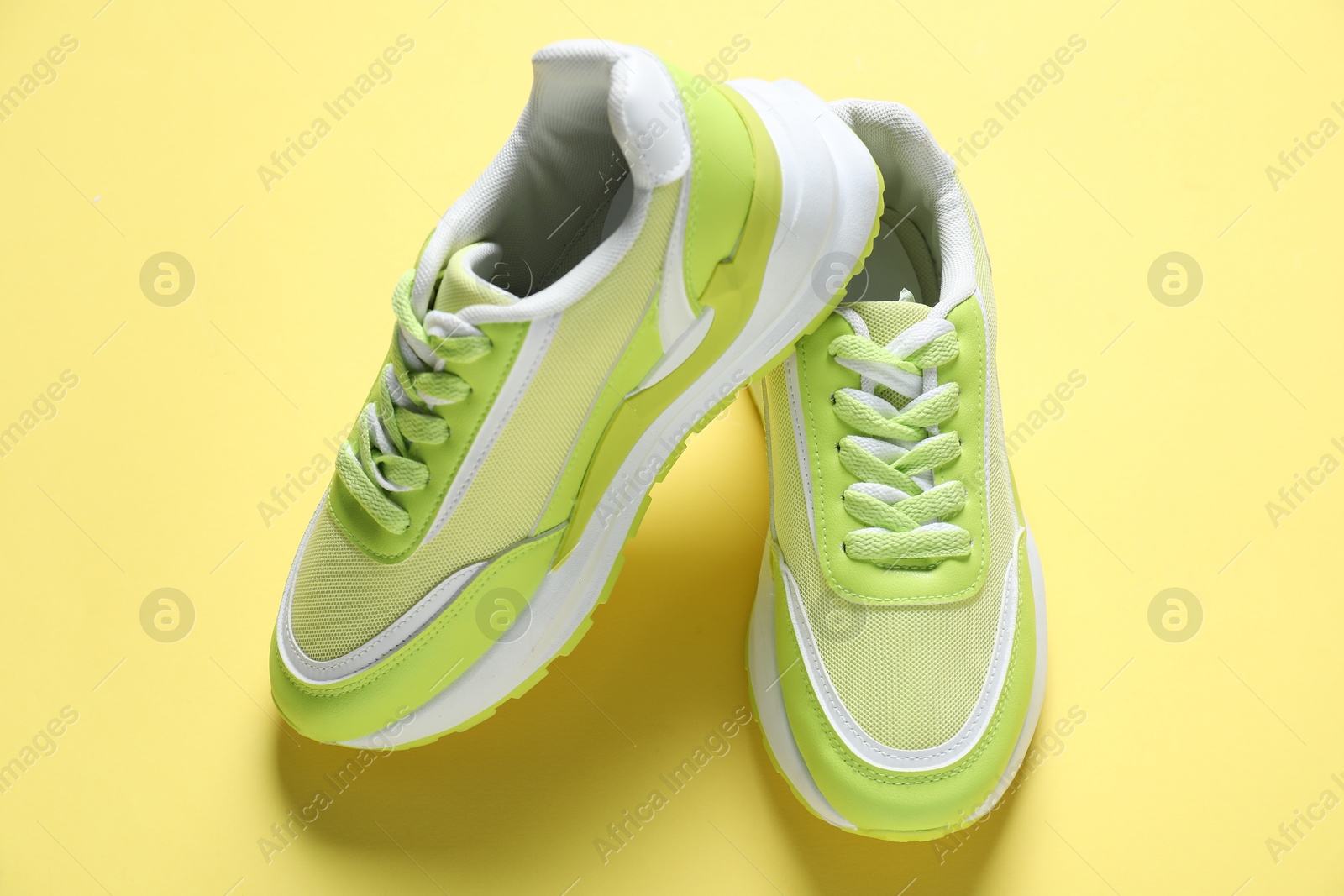 Photo of Green sneakers on yellow background, above view. Sportive shoes