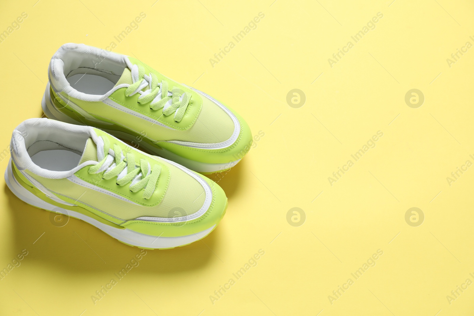 Photo of Sportive shoes. Green sneakers on yellow background, above view. Space for text