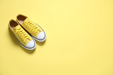 Photo of Sportive shoes. Color sneakers on yellow background, flat lay. Space for text