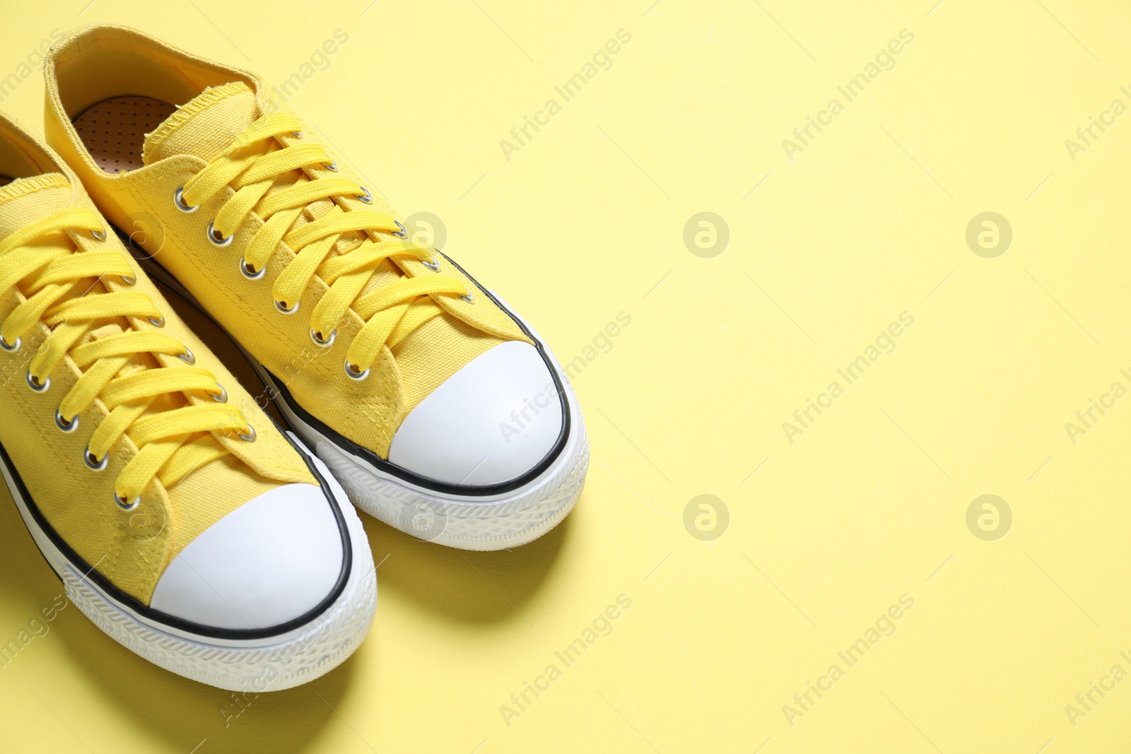 Photo of Sportive shoes. Color sneakers on yellow background, closeup. Space for text