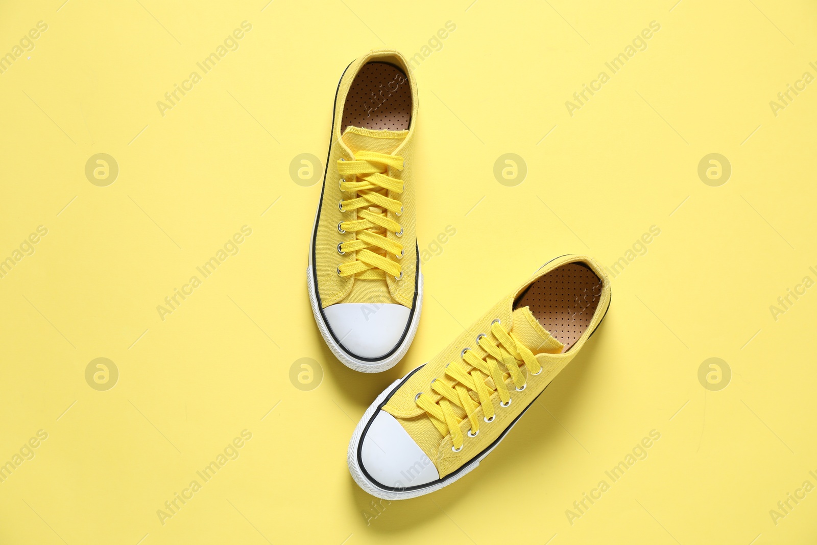 Photo of Color sneakers on yellow background, flat lay. Sportive shoes