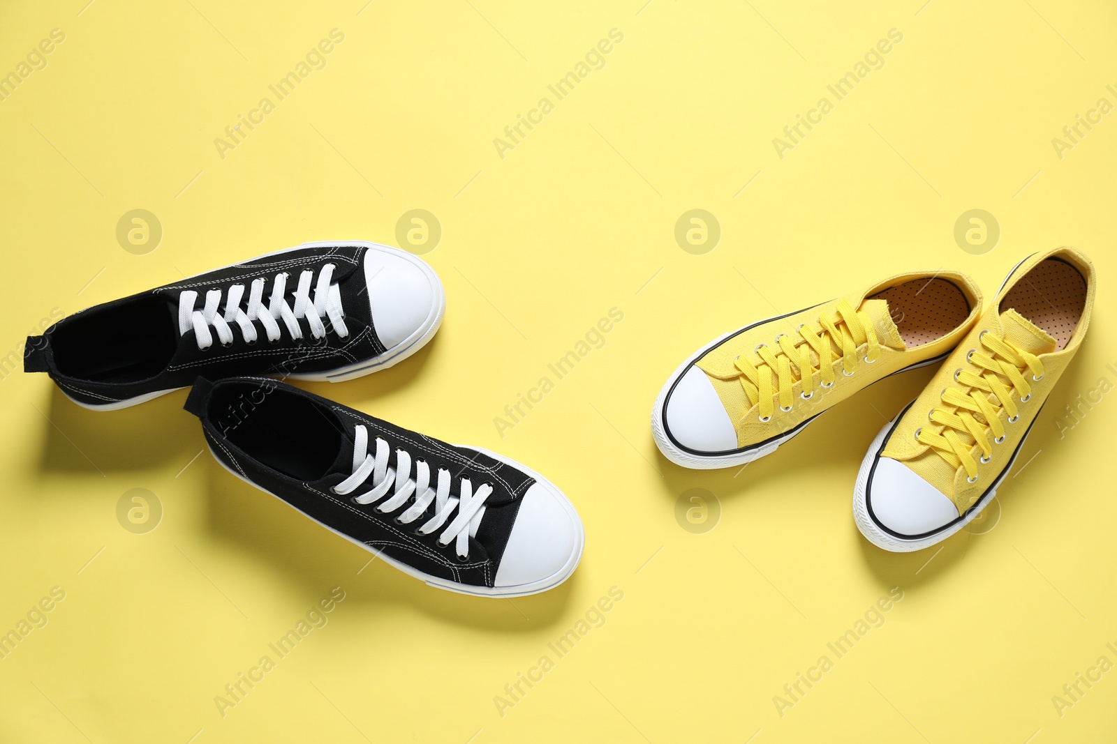 Photo of Colorful sneakers on yellow background, flat lay. Sportive shoes