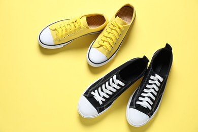 Photo of Colorful sneakers on yellow background, flat lay. Sportive shoes