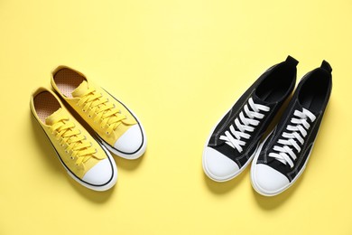 Photo of Colorful sneakers on yellow background, flat lay. Sportive shoes