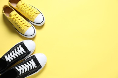 Photo of Sportive shoes. Colorful sneakers on yellow background, flat lay. Space for text