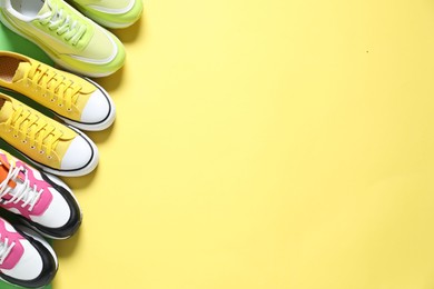 Photo of Sportive shoes. Different sneakers on yellow background, flat lay. Space for text