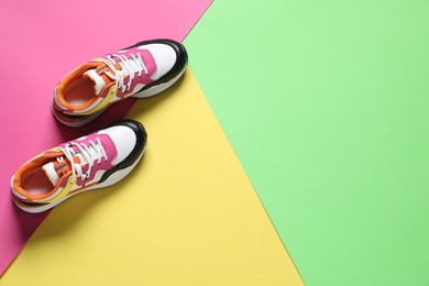 Photo of Sportive shoes. Colorful sneakers on color background, flat lay. Space for text