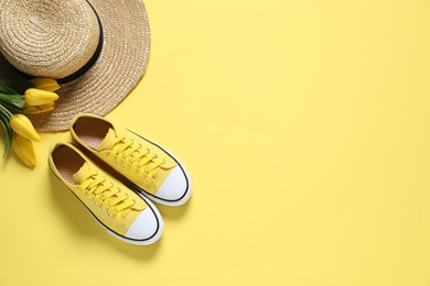 Photo of Stylish shoes, straw hat and tulips on yellow background, flat lay. Space for text