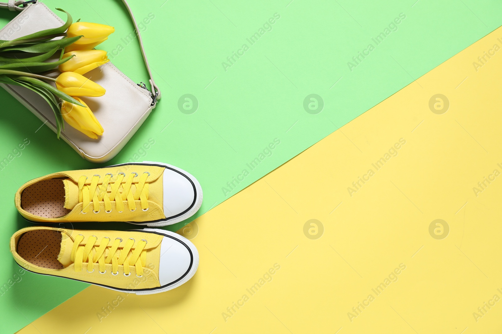 Photo of Stylish shoes, bag and yellow tulips on color background, flat lay. Space for text