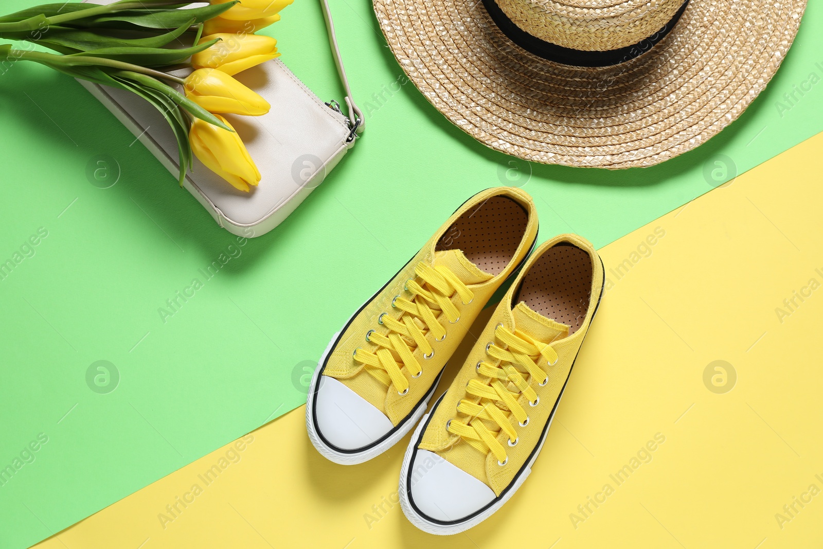 Photo of Stylish shoes, bag, hat and yellow tulips on color background, flat lay