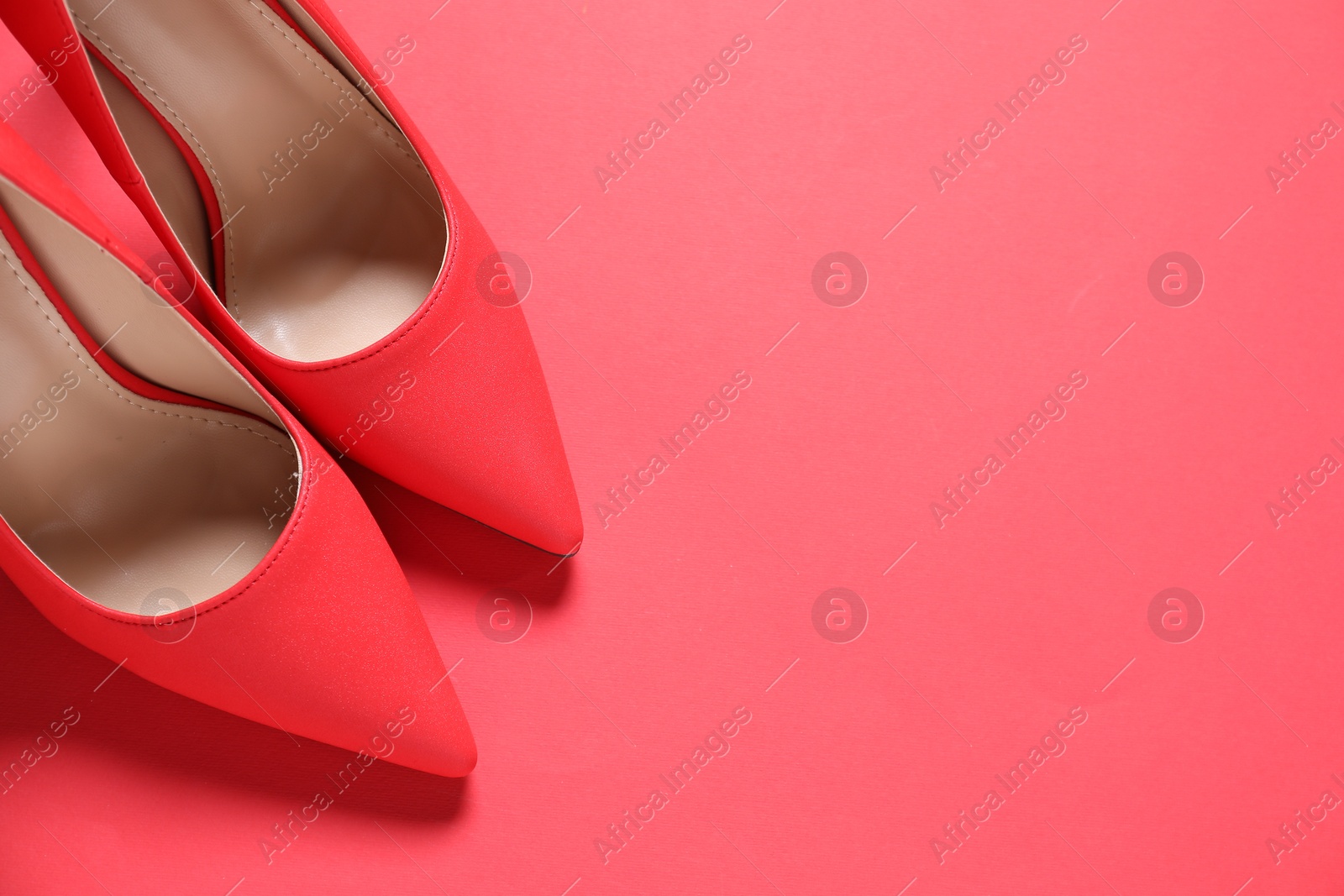 Photo of High heeled shoes on crimson background, flat lay. Space for text