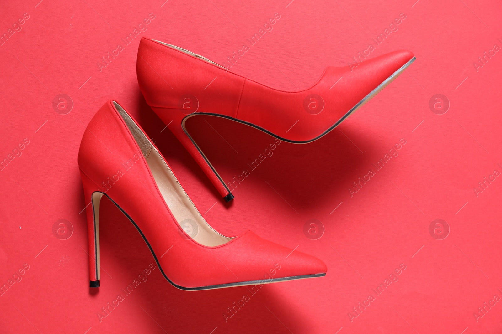 Photo of High heeled shoes on crimson background, flat lay