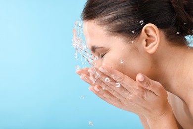 Photo of Woman washing her face on light blue background. Space for text