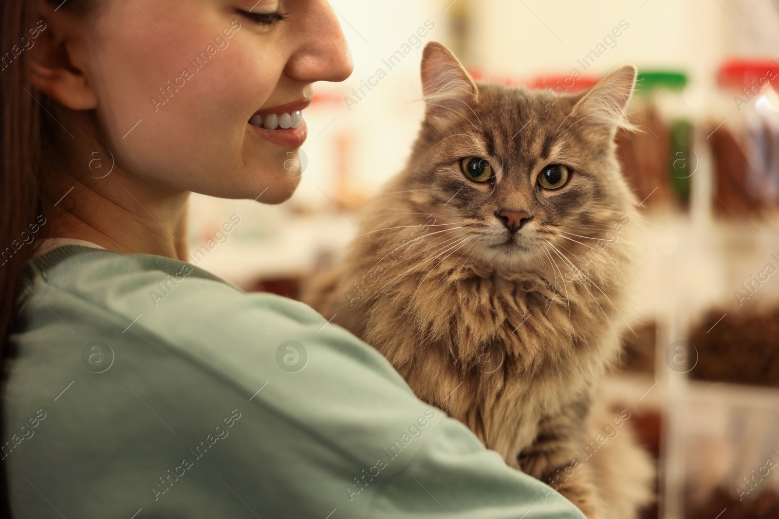 Photo of Woman with her cute cat in pet shop, closeup