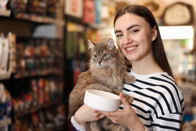 Photo of Woman with her cute cat and feeding bowl in pet shop. Space for text