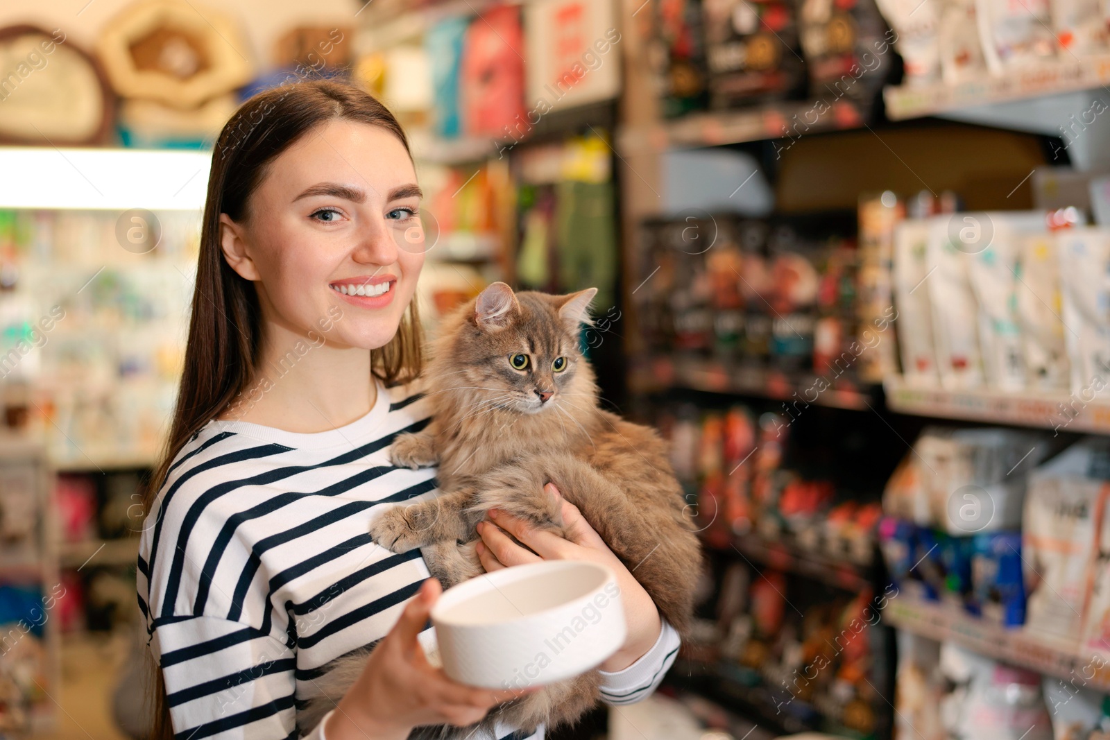 Photo of Woman with her cute cat and feeding bowl in pet shop. Space for text