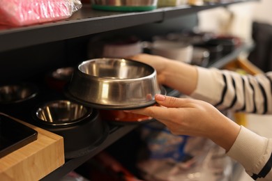 Photo of Woman choosing feeding bowl in pet shop, closeup