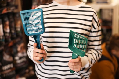 Photo of Woman with litter scoops in pet shop, closeup