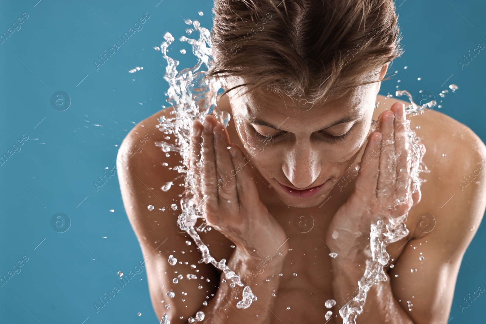 Photo of Handsome man washing his face on blue background