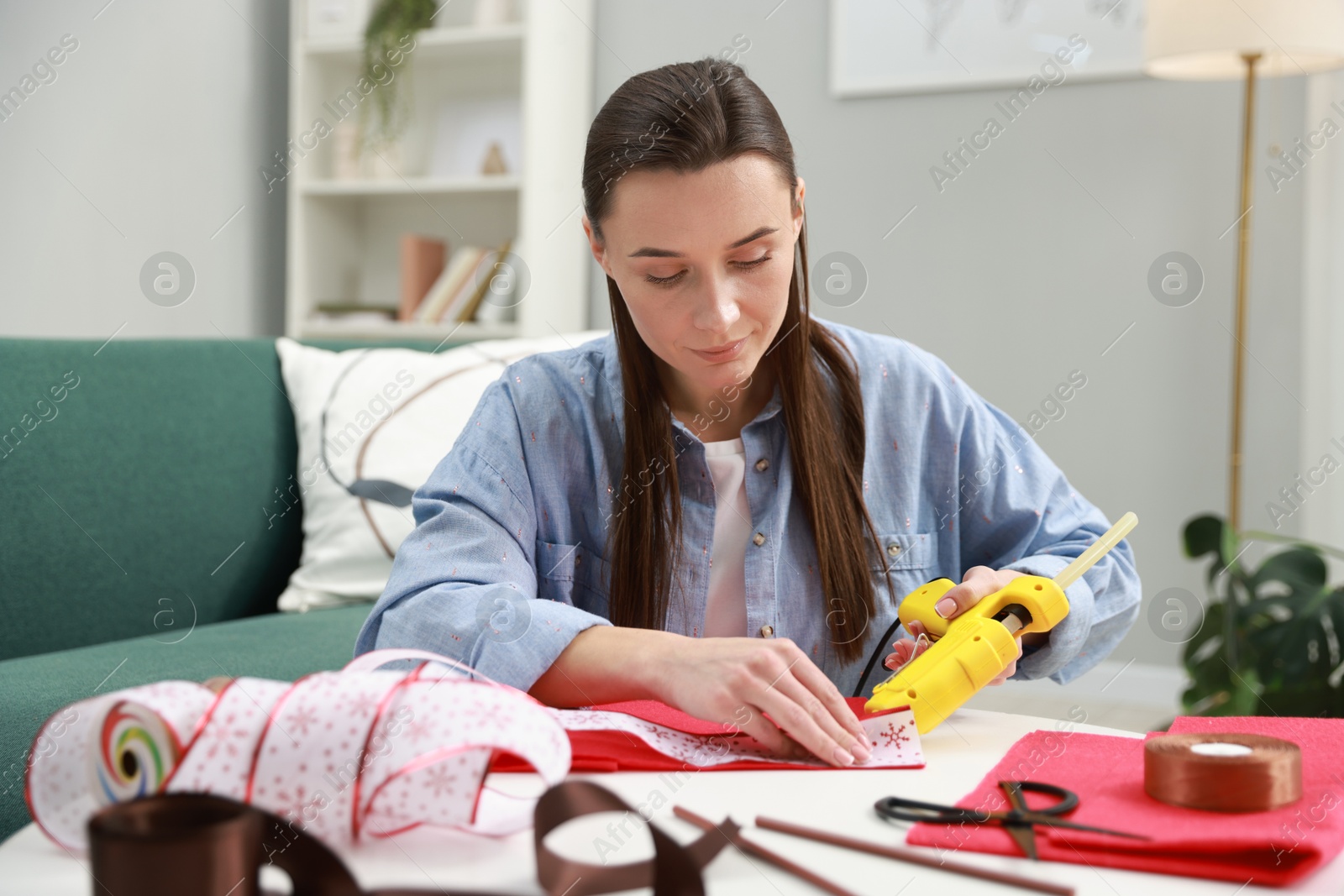 Photo of Woman with hot glue gun making craft at table indoors