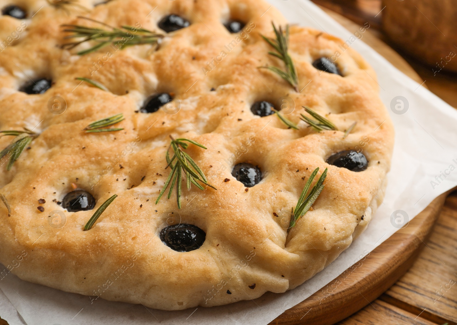 Delicious focaccia bread with olives and rosemary on wooden table, closeup Photo of Delicious focaccia bread with olives and rosemary on wooden table, closeup