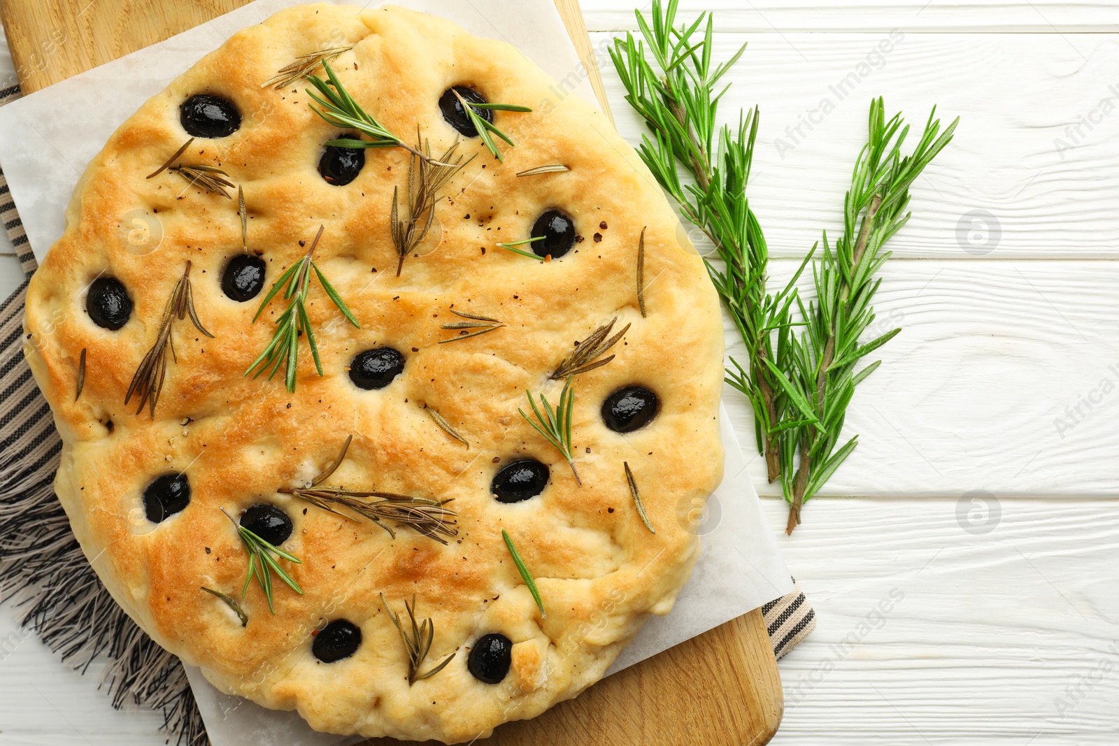 Delicious focaccia bread with olives and rosemary on white wooden table, top view Photo of Delicious focaccia bread with olives and rosemary on white wooden table, top view