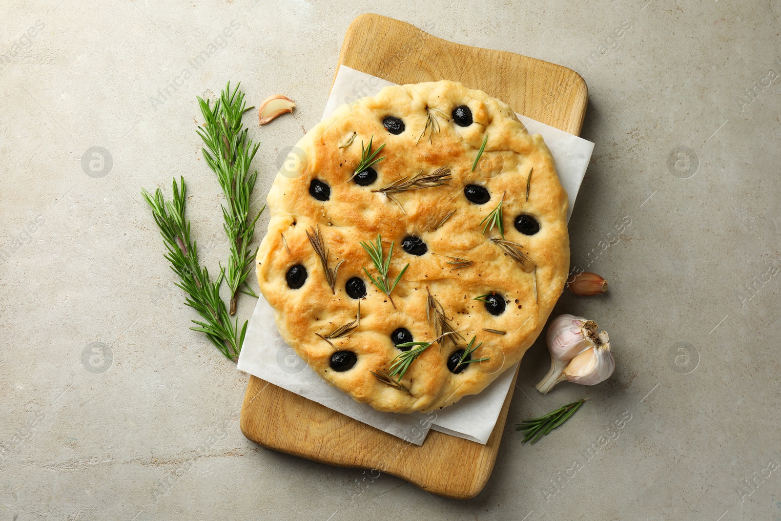 Delicious focaccia bread with olives, rosemary and garlic on grey table, flat lay Photo of Delicious focaccia bread with olives, rosemary and garlic on grey table, flat lay