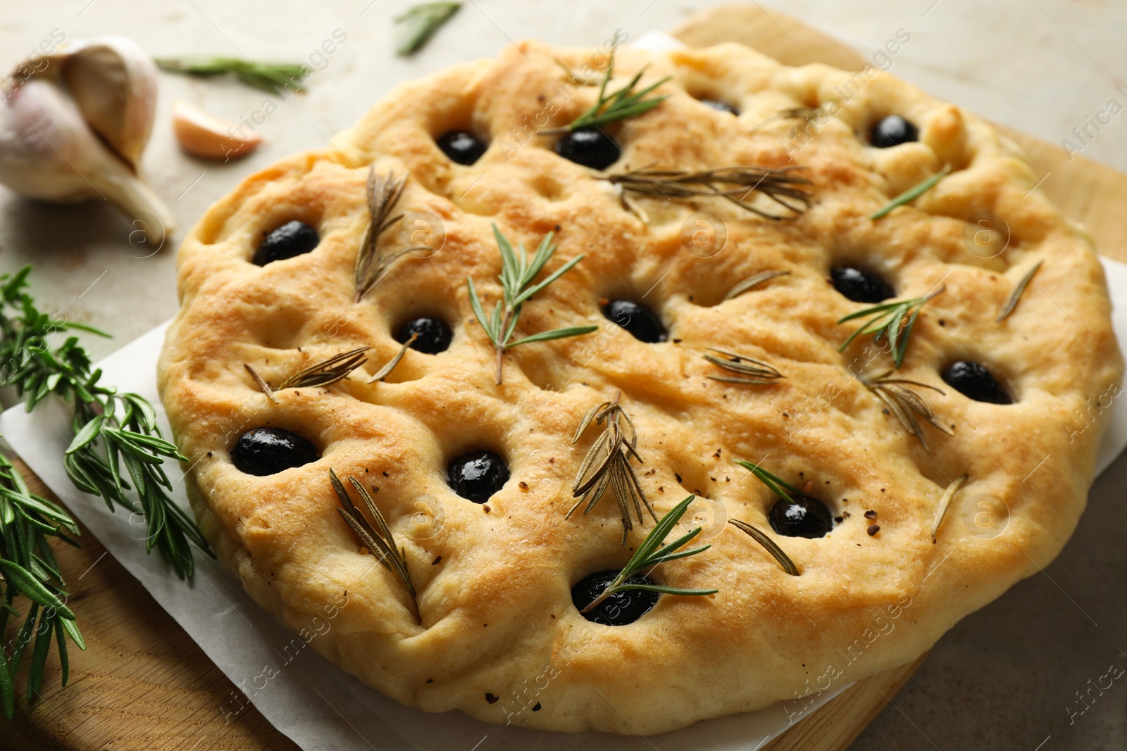Delicious focaccia bread with olives, rosemary and garlic on grey table, closeup Photo of Delicious focaccia bread with olives, rosemary and garlic on grey table, closeup