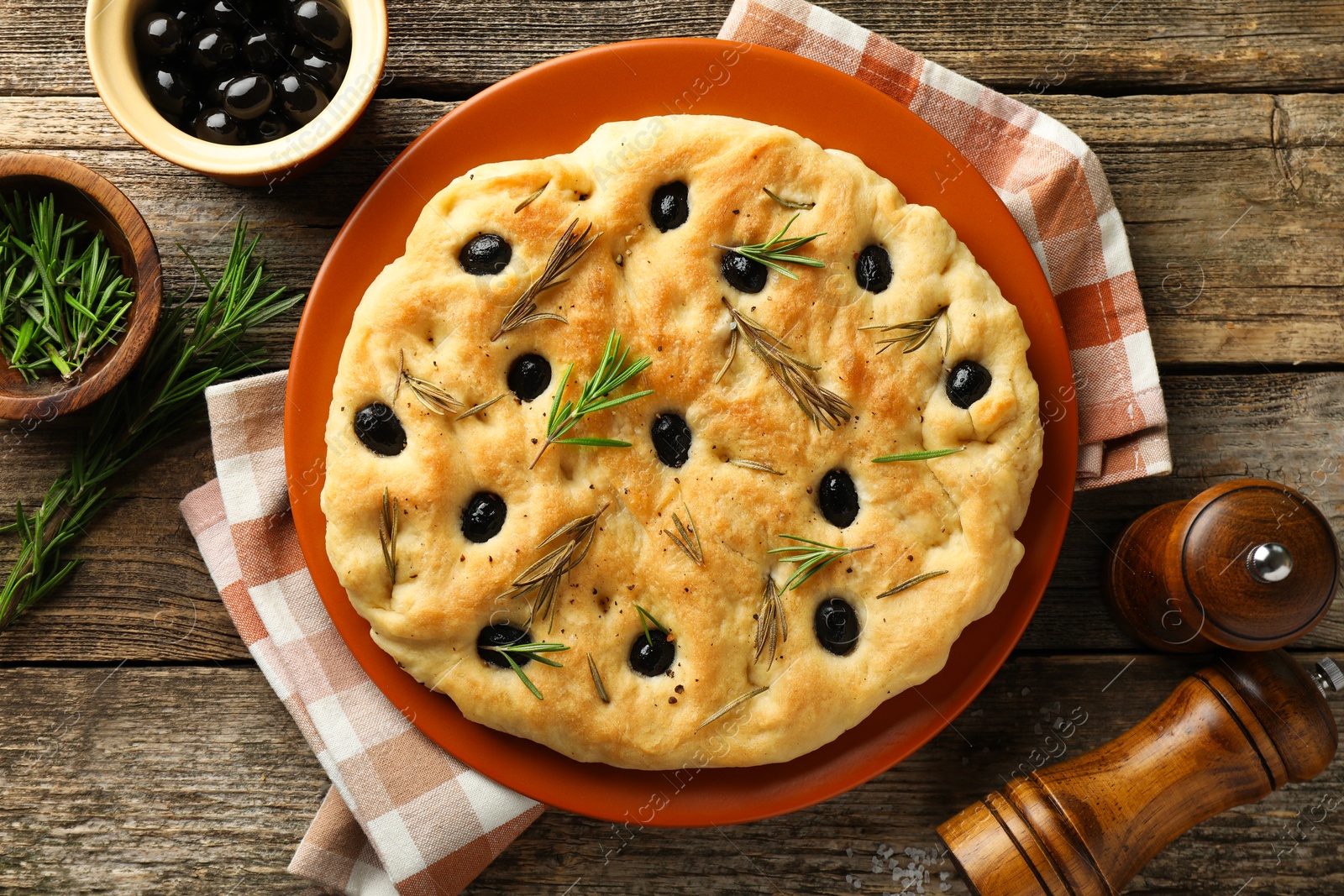 Delicious focaccia bread with olives, rosemary and spices on wooden table, flat lay Photo of Delicious focaccia bread with olives, rosemary and spices on wooden table, flat lay