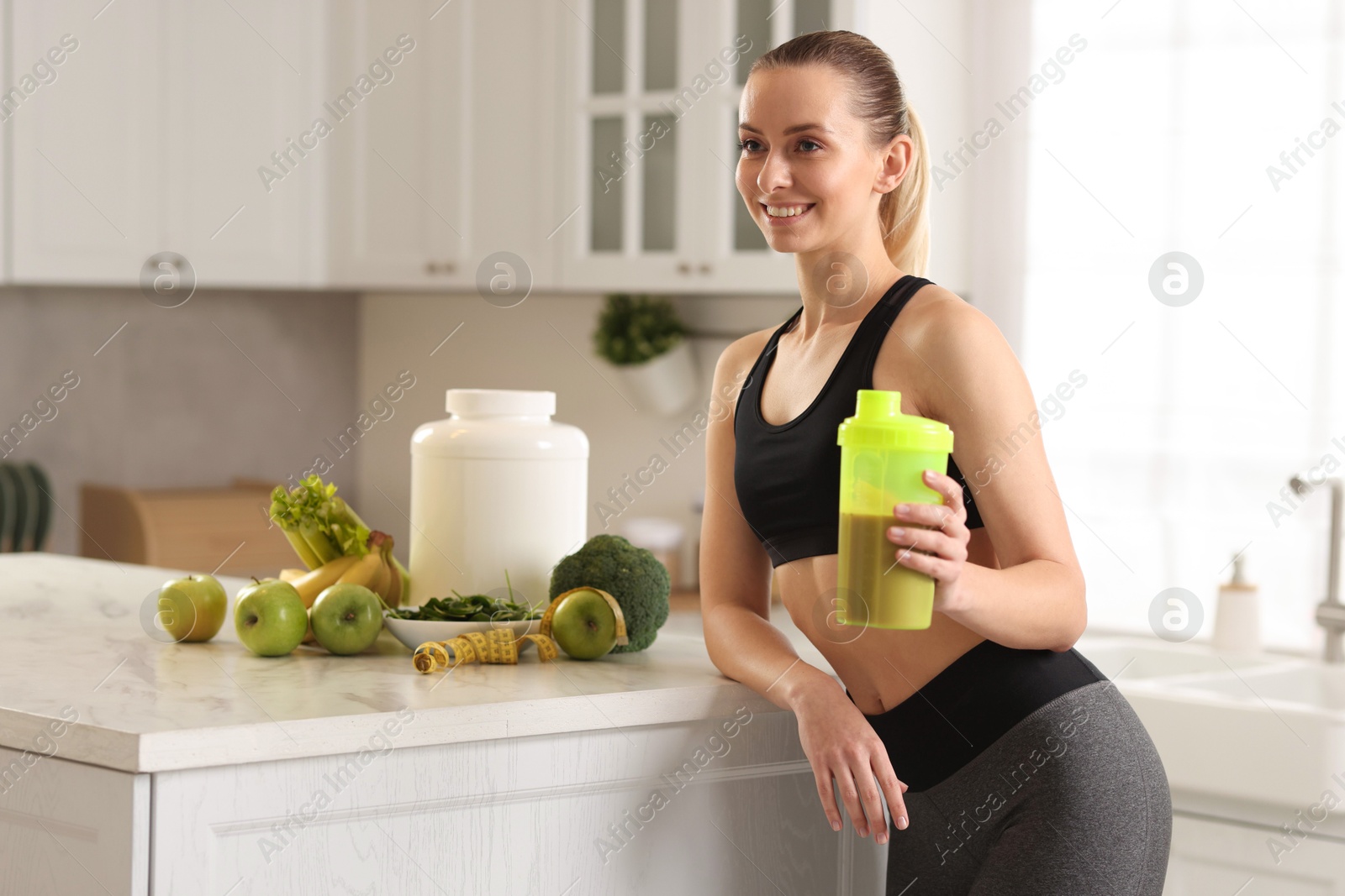 Photo of Weight loss. Happy woman with shaker of protein in kitchen