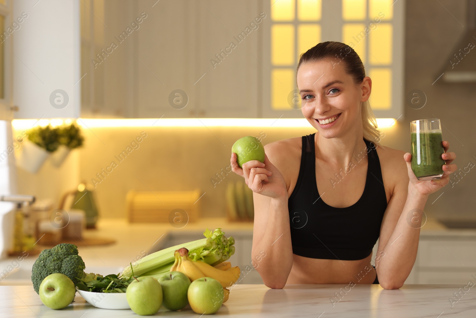 Photo of Weight loss. Happy woman with healthy shake and apple at white marble table in kitchen