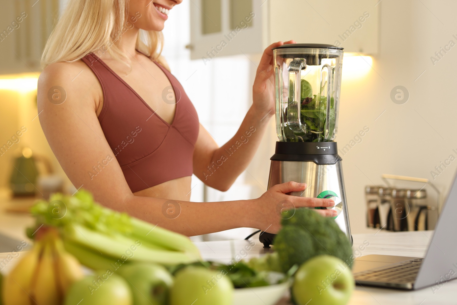 Photo of Weight loss. Woman making protein shake at table in kitchen, closeup