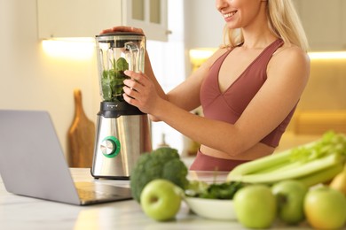 Photo of Weight loss. Woman making protein shake at table in kitchen, closeup