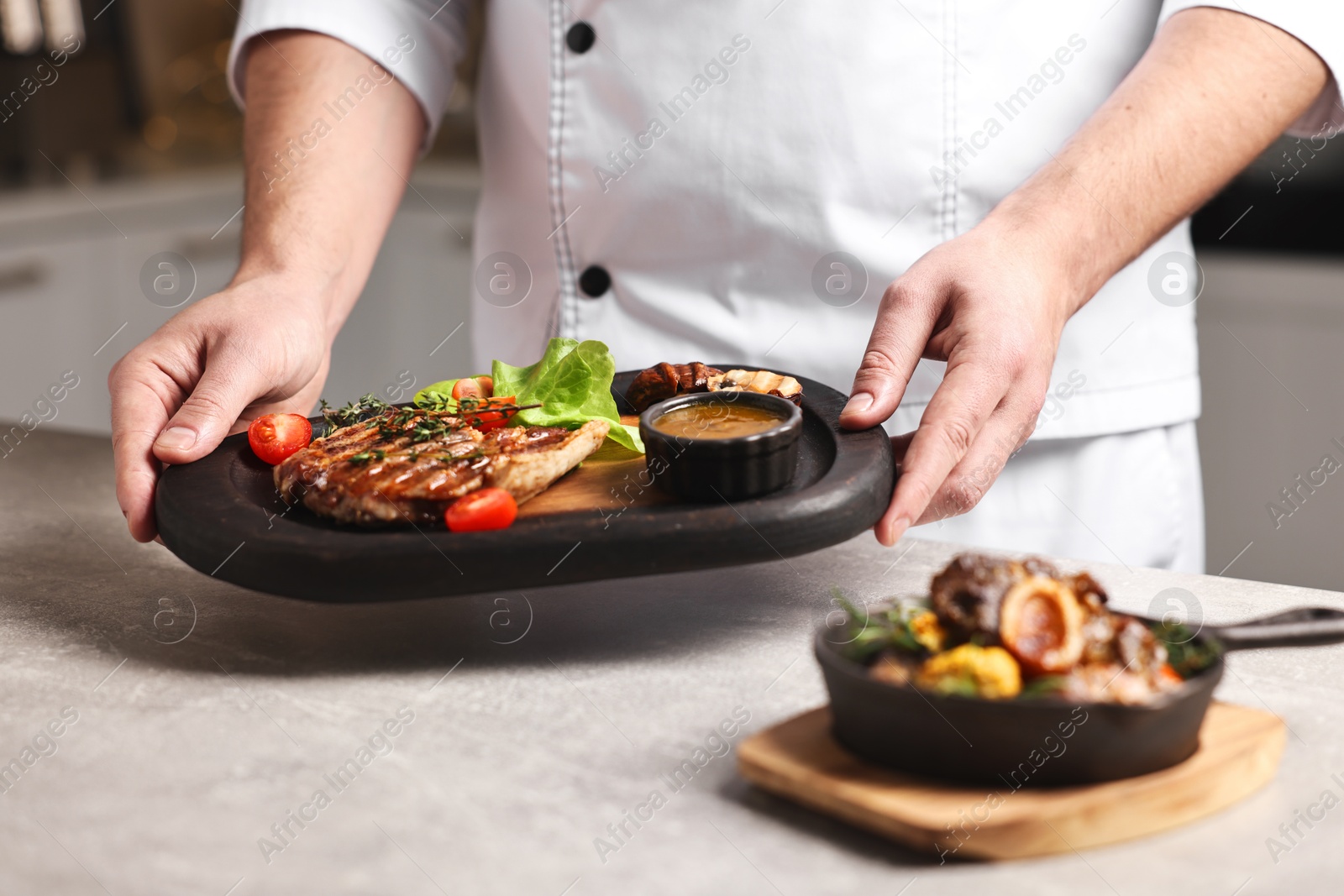 Photo of Professional chef serving dish at table indoors, closeup