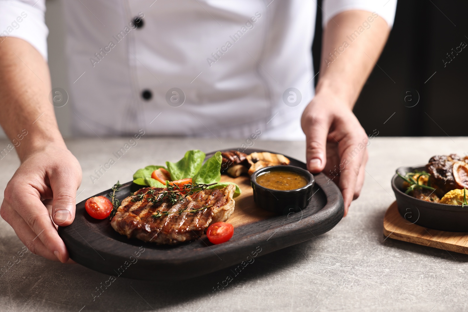 Photo of Professional chef serving dish at table indoors, closeup